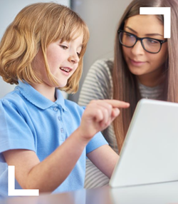 Primary-aged girl using an ipad with her teacher