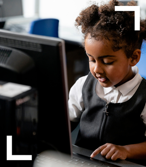 Primary girl in school uniform using school computer