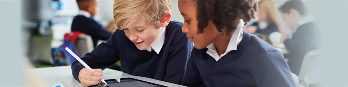 Two children in school uniform looking at lesson papers in a classroom