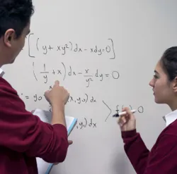 students in class working on an equation on a whiteboard