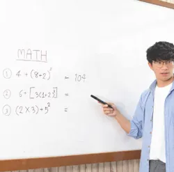 student in class explaining equation on whiteboard