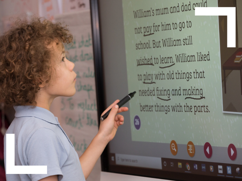 Young boy using Reading Planet Online on interactive whiteboard