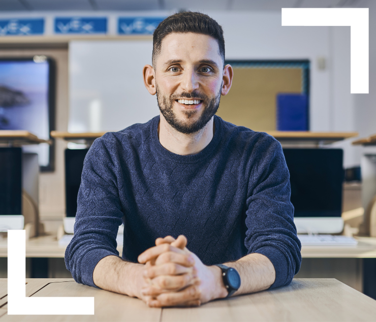 Teacher sitting at desk smiling